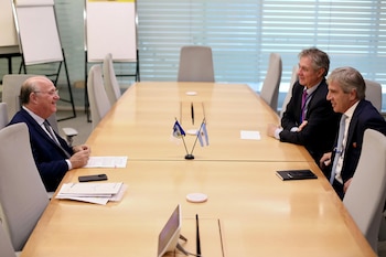 Tres hombres sentados alrededor de una mesa de reuniones de madera clara en una sala moderna. En el centro de la mesa hay dos pequeñas banderas, una de Argentina y otra del BID