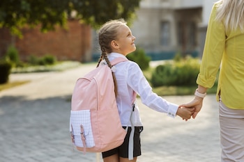 Una niña yendo al colegio con su madre