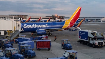 Un avión azul y rojo de Southwest Airlines está estacionado en una puerta del Aeropuerto Internacional de Nashville, con vehículos de servicio y personal de tierra en la pista