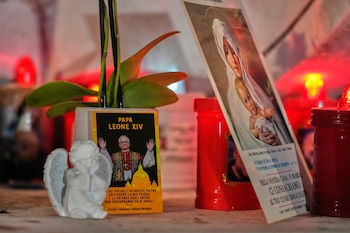 Una imagen del papa León XIV descansa en la base de una estatua del difunto Juan Pablo II frente a la Policlínica Agostino Gemelli, donde León está hospitalizado para una cirugía para remover un nódulo pulmonar, en Roma, el 13 de octubre de 2026. (Foto AP/Gregorio Borgia)