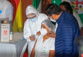 El presidente de Bolivia, Luis Arce (d), atestigua la primera vacunación contra la covid-19 del país a la enfermera Sandra Ríos (c), tras la llegada de las primeras 20.000 dosis de la rusa Sputnik V, hoy, en el Hospital Japonés de Santa Cruz
