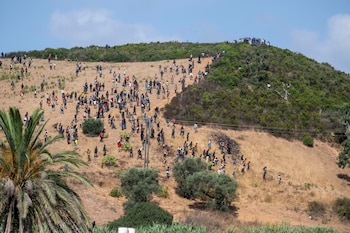 Varios migrantes se reúnen en una colina mientras intentan cruzar desde la ciudad fronteriza de Fnideq hacia el enclave español de Ceuta. (AP Foto)