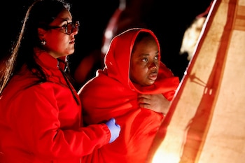 Una trabajadora de la Cruz Roja acompaña a un migrante para que reciba asistencia de la Cruz Roja tras llegar en una embarcación de fibra de vidrio a la playa de Castillo del Romeral, el 29 de diciembre de 2024. (REUTERS/Borja Suárez)