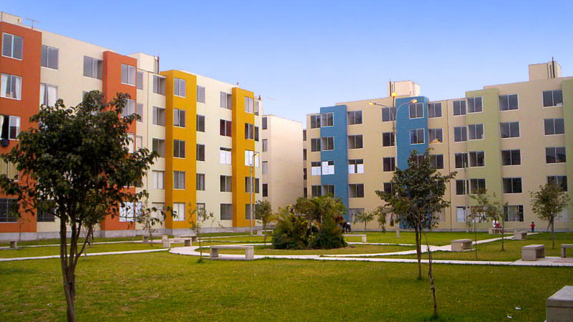 Un conjunto de edificios de departamentos con fachadas de colores y áreas verdes ilustra la necesidad de aumentar la oferta de viviendas en Perú, donde el déficit habitacional es considerable. (Imagen Ilustrativa Infobae)