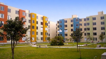 Conjunto de edificios de apartamentos de varios pisos con fachadas coloridas, con áreas verdes, árboles, arbustos, caminos y bancos de hormigón