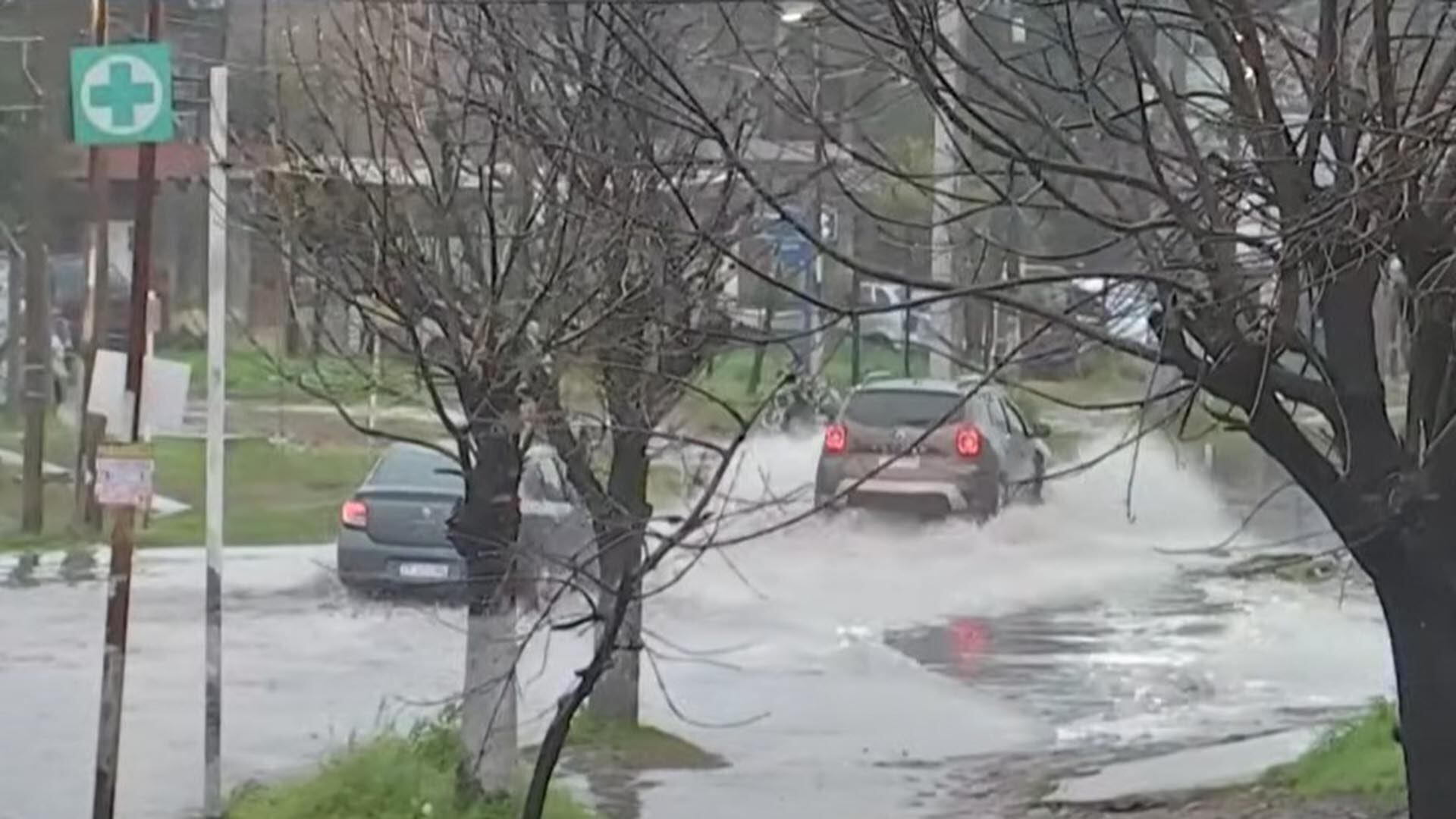 Dos autos tratan de pasar sobre una avenida inundada, en Villa Celina.