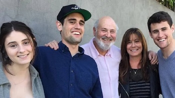 Rob Reiner, Michele Singer Reiner y Nick Reiner sonríen de pie frente a una pared de cemento, acompañados de otros dos jóvenes a los lados