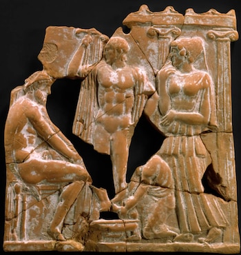 Fragmento de relieve en terracota con cuatro figuras: un hombre de pie y tres personas sentadas o arrodilladas. Presenta pilares y secciones rotas sobre fondo negro