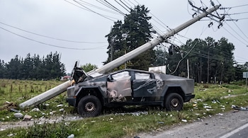 Camioneta Tesla Cybertruck siniestrada junto a una carretera bajo un poste de concreto inclinado, con cables sueltos y bolsas de aire desplegadas.