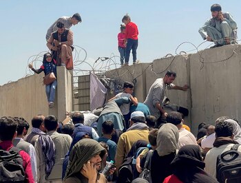 La gente intenta saltar la pared que los separa del aeropuerto de Kabul para abordar los vuelos de repatriación enviados por EE.UU