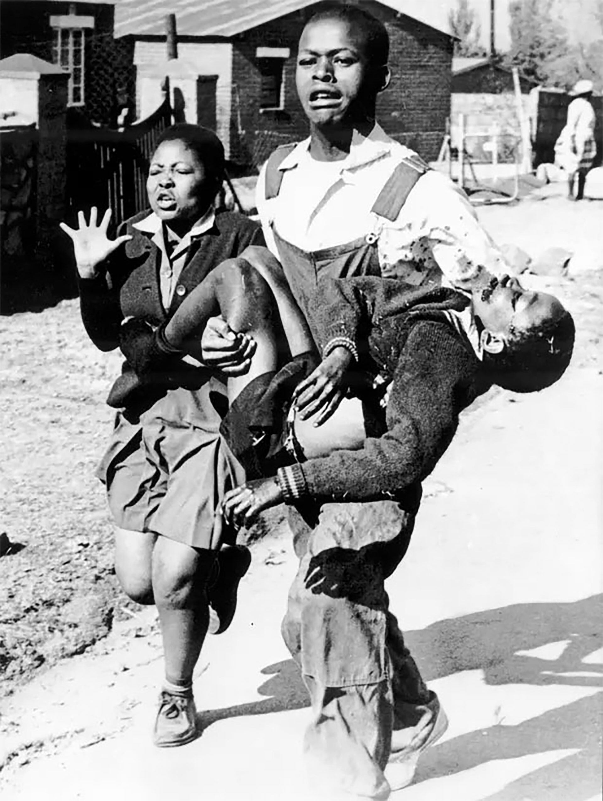 Hector cayó en el cruce de las calles Moema y Vilakazi. Está en brazos de Mbuyisa Makhubo, otro estudiante, de 18 años. A su lado, desesperada e implorando ayuda, va Antoinette, de 17, su hermana (AP/Sam Nzima)