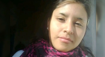 Una joven con bufanda de tonos fucsia y negro mira a la cámara en un primer plano