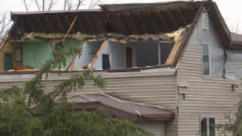 Casa en Wausau con el techo superior visiblemente dañado y arrancado, exponiendo las habitaciones interiores y la estructura de madera. Árbol en primer plano