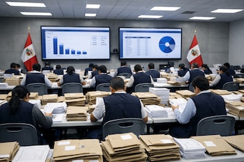 Sala de conteo oficial de la ONPE en Perú. Funcionarios con chalecos azules revisan pilas de sobres y actas electorales; dos pantallas grandes con gráficos y banderas de Perú.