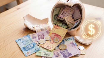 Alcancía de cerámica rota con billetes y monedas mexicanas desbordándose sobre mesa de madera clara; un círculo digital con signo de pesos brilla al lado.