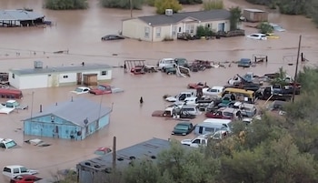 Vista aérea de varias casas y decenas de automóviles sumergidos en agua turbia rodeados de vegetación