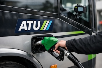 Primer plano de una mano repostando un bus urbano con una manguera de combustible verde; el logo de la ATU y un dispositivo GPS son visibles en el vehículo.