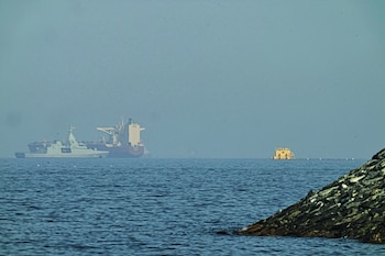 Una patrullera emiratí (izquieda), navega cerca de un petrolero fondeado en el golfo de Omán, cerca del estrecho de Ormuz, vistos desde una carretera costera cerca de Khor Fakkan, Emiratos Árabes Unidos, el 1 de mayo de 2026. (AP Foto/Fatima Shbair)