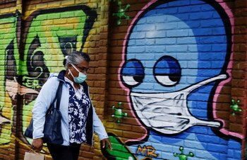 Foto de archivo. Una mujer con una mascarilla protectora camina junto a una pared con graffitisen San José, Costa Rica el 13 de julio de 2020. REUTERS/Juan Carlos Ulate