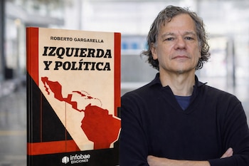 Un hombre con cabello gris y barba, vestido con suéter oscuro, posa junto a un libro con la tapa de color beige y negro que muestra un mapa de América Latina.