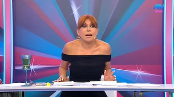Magaly Medina viste un vestido negro y apoya sus manos sobre un escritorio con papeles en un set de televisión