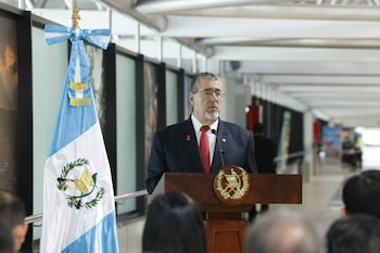 Bernardo Arévalo habla desde un podio con el escudo nacional, situado junto a la bandera de Guatemala y frente a varias personas