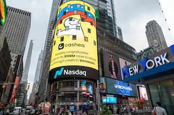 Pantalla digital de Nasdaq en Times Square con logo de Cashea, personaje sonriente y bandera de Venezuela, rodeada de rascacielos y peatones