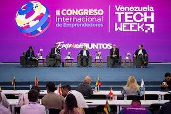 Cinco hombres sentados en un escenario frente a una pantalla con los logos del "II Congreso Internacional de Emprendedores" y "Venezuela Tech Week"