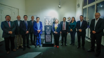 Un grupo de personas posa alrededor de un pedestal con dos esculturas pequeñas dentro de una sala de museo