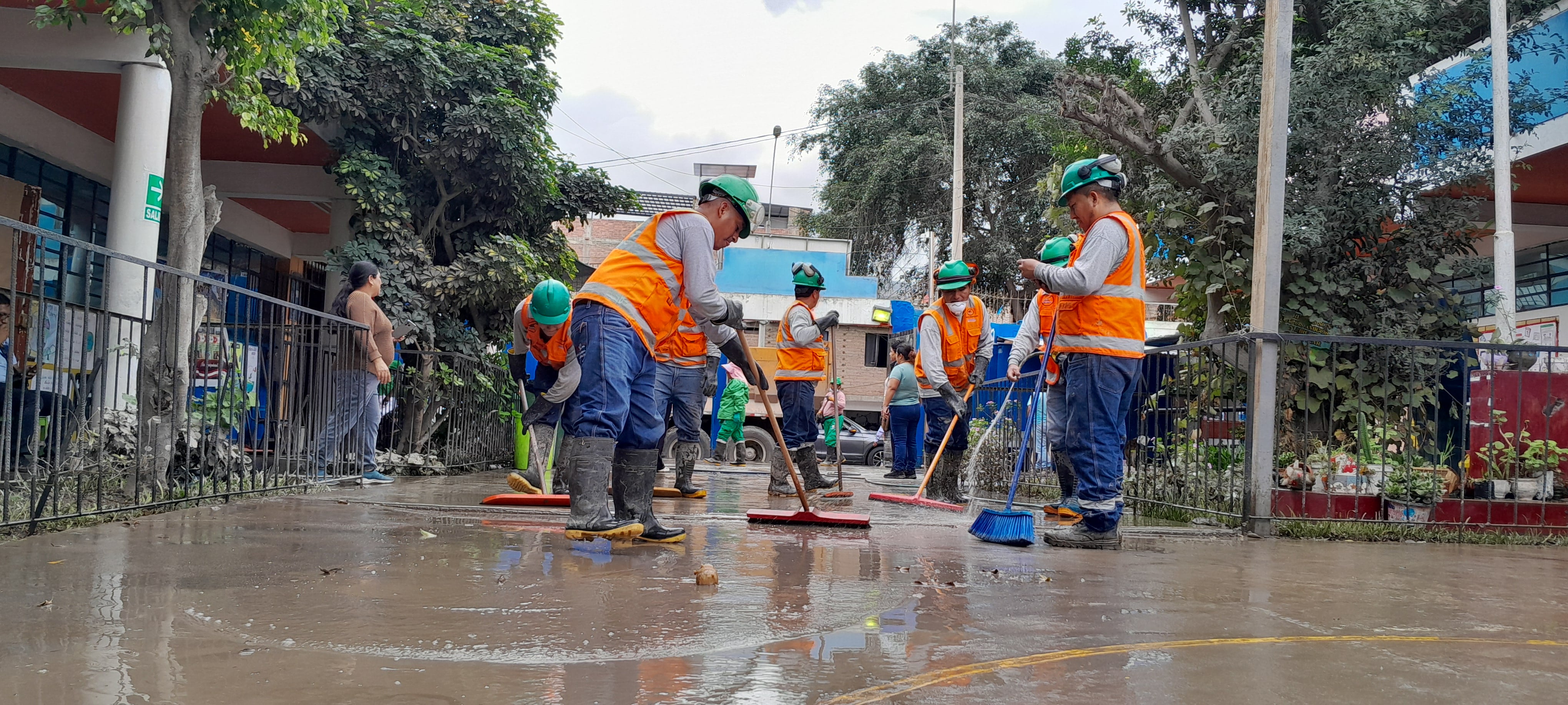Personal de limpieza remueve el agua de aniegos y aguas residuales del patio de la I.E. N.° 7092 Juan Pablo II en Villa El Salvador, Lima Sur, tras las recientes lluvias.