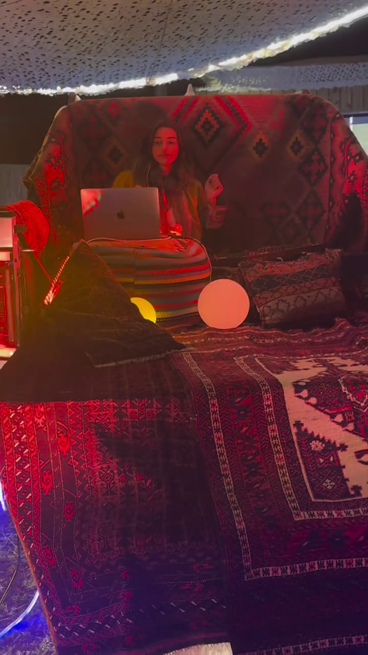 Calu Rivero dispara música desde su laptop rodeada de textiles con patrones vibrantes y luces cálidas, creando un espacio de trabajo único y confortable (IG lacalurivero)