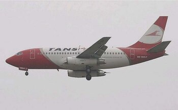 Un avión comercial de color rojo y blanco con la inscripción TANS Perú vuela en el cielo con el tren de aterrizaje desplegado