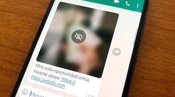 Primer plano de un teléfono móvil con la aplicación WhatsApp abierta, mostrando un mensaje con una imagen difuminada y un icono de ojo tachado, junto a un enlace.
