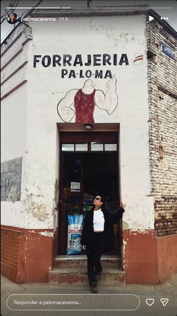 Paloma Cavanna de pie frente a una forrajería con el nombre 'FORRAJERIA PA-LO-MA' y un dibujo de paloma musculosa en la fachada desgastada