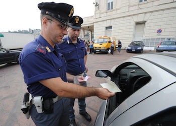 Un policía italiano revisa los documentos de un conductor en Génova, Italia. (EFE/LUCA ZENNARO)