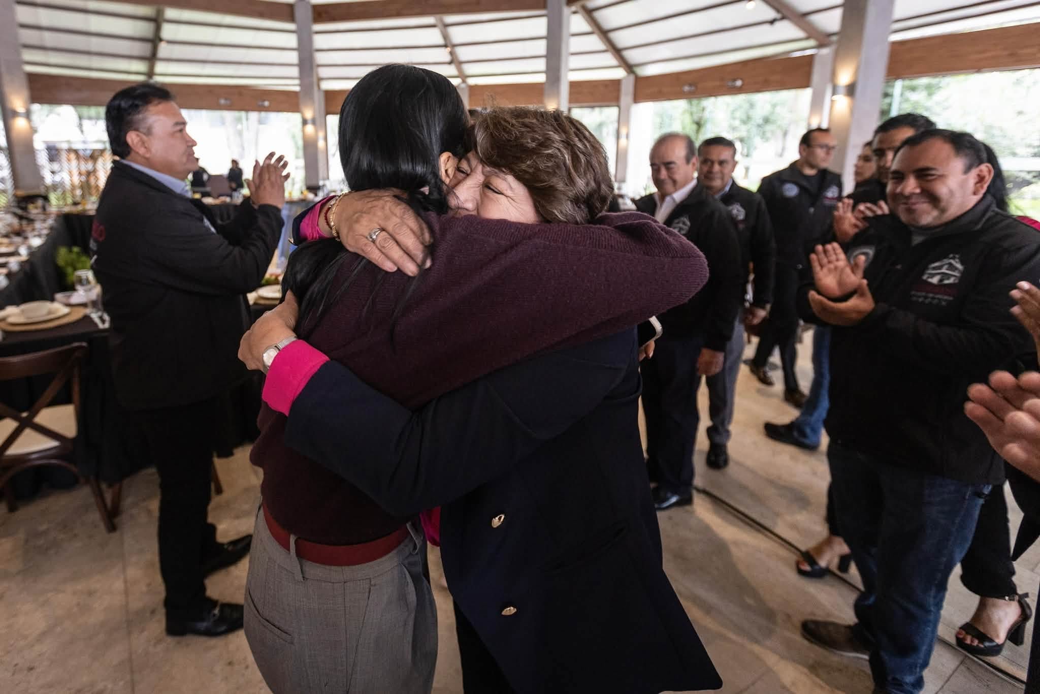 Delfina Gómez y Ariadna Montiel Reyes se abrazan entre los aplausos de los asistentes a un evento en el Estado de México. (Ariadna Montiel Reyes )