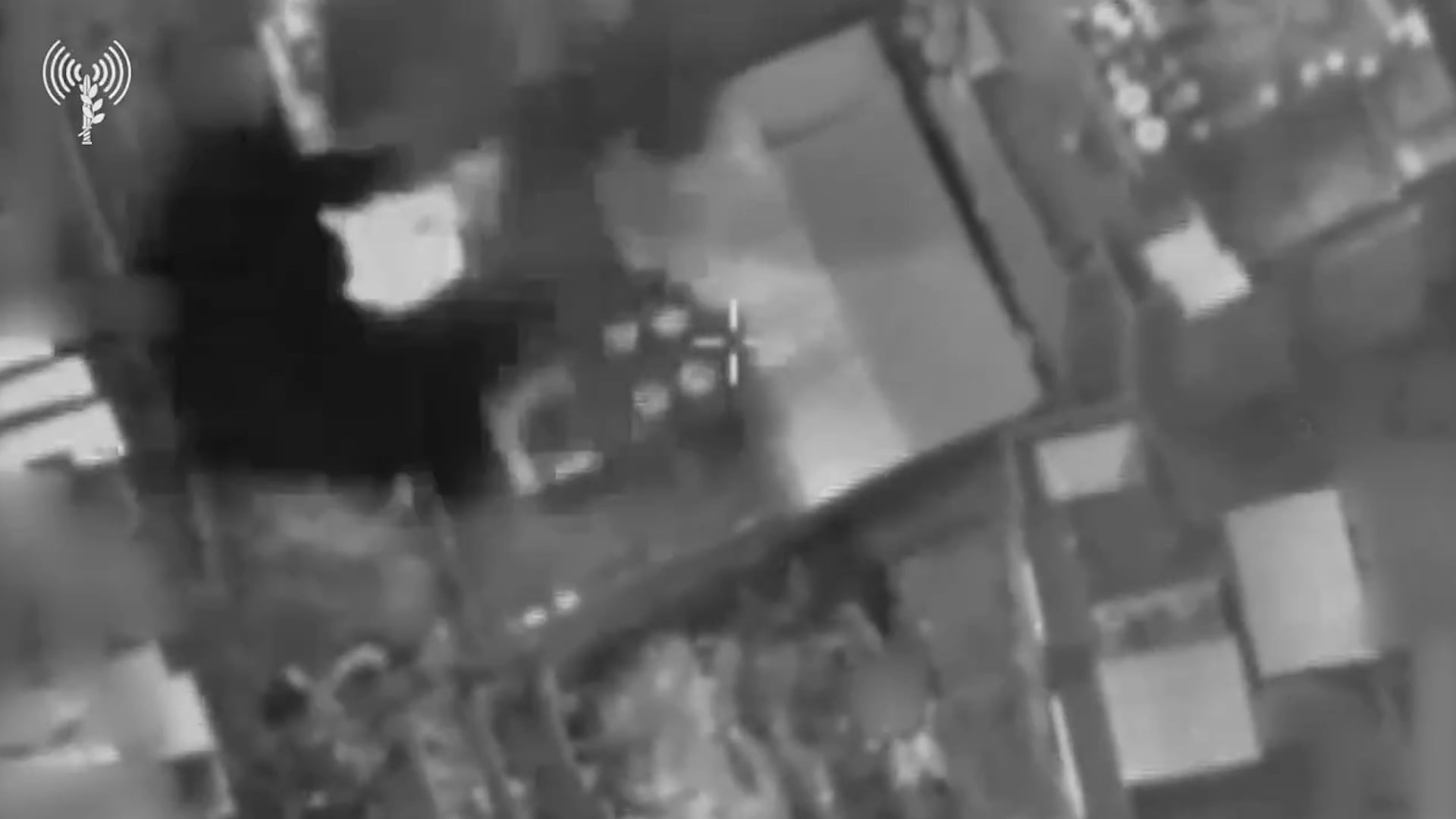 Una vista aérea en blanco y negro de una zona edificada, mostrando un objetivo marcado por un retículo en el centro