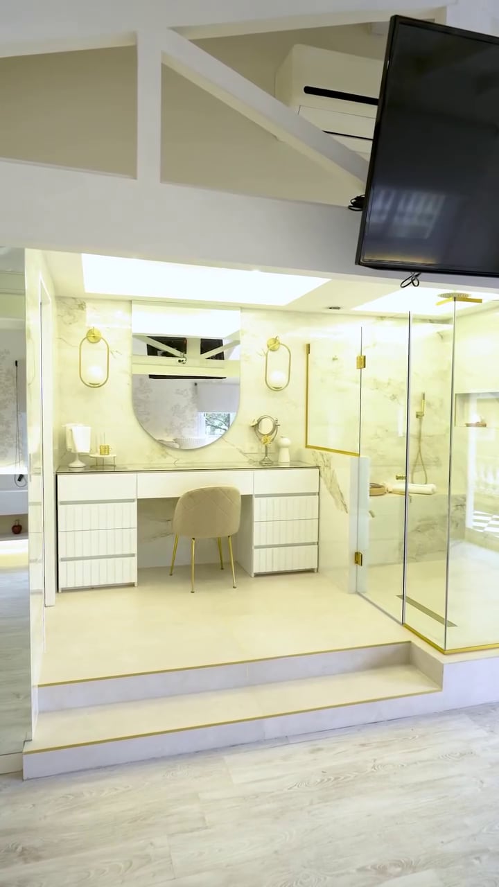 La remodelada suite de Moria Casán cuenta con un sector de tocador blanco con espejo ovalado y una ducha con mampara de vidrio y detalles dorados.