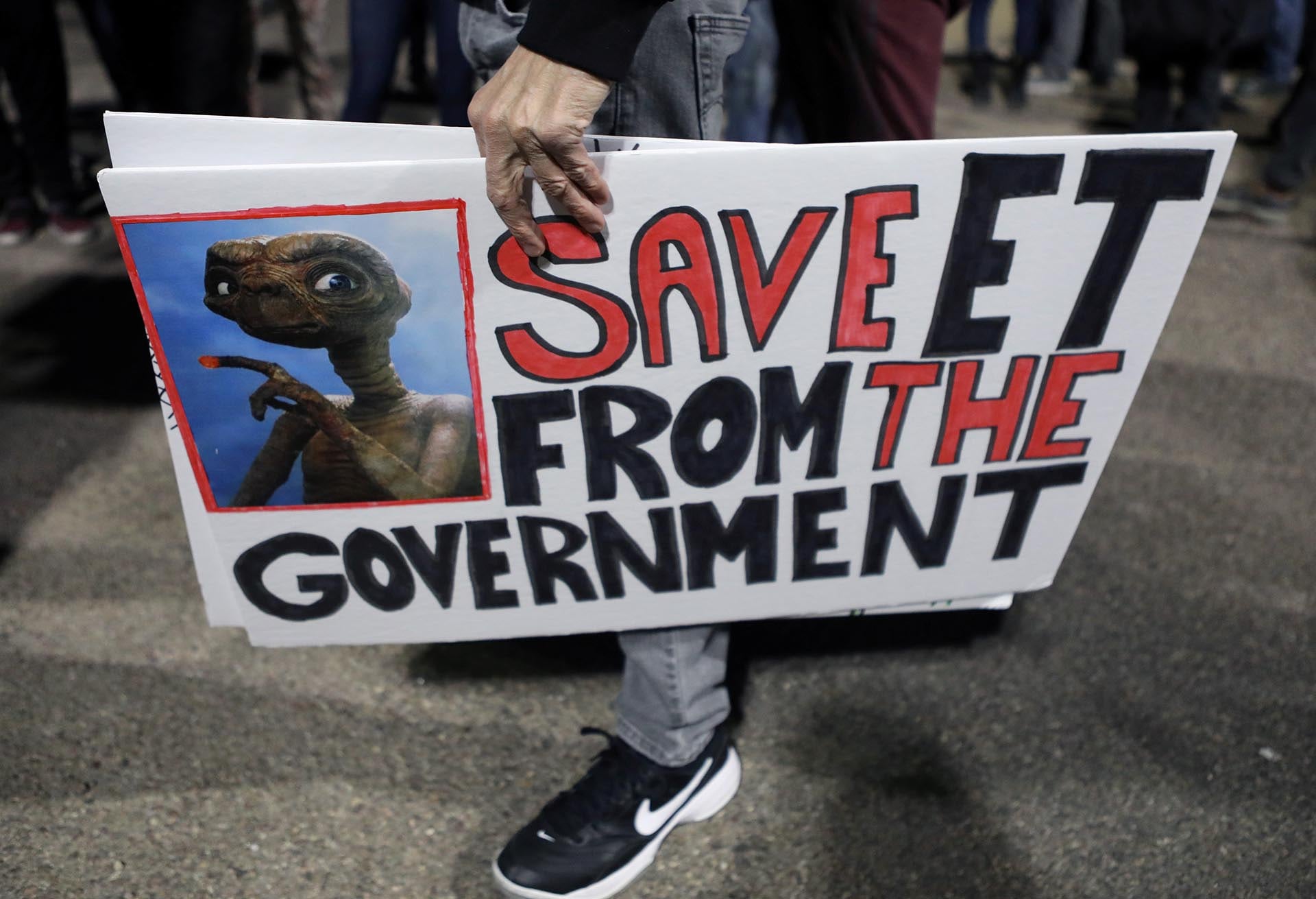 Una persona porta carteles frente a la entrada del Área 51, mientras se espera una afluencia de turistas que responden a un llamado a