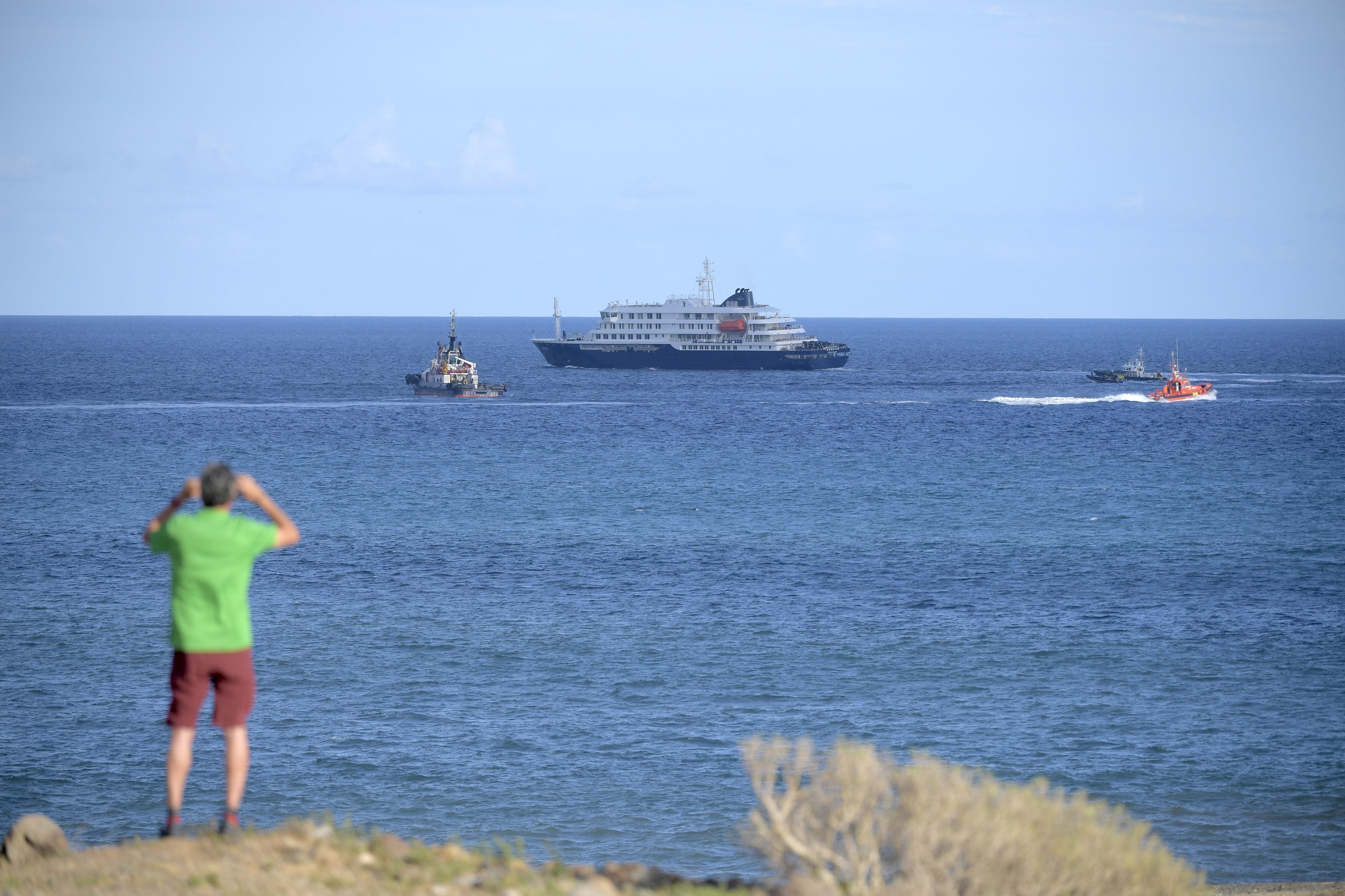Un hombre fotografía el crucero MV Hondius mientras este abandona el puerto de Granadilla (Tenerife). (Jorge Guerrero/AFP)