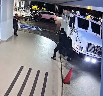 Cámaras de seguridad captaron a tres hombres encapuchados acercándose al camión blindado mientras los custodios realizaban el traslado del dinero. Captura de video