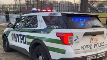 Primer plano de la parte trasera y lateral de un SUV policial híbrido blanco y verde del NYPD con luces de emergencia azules y rojas intermitentes
