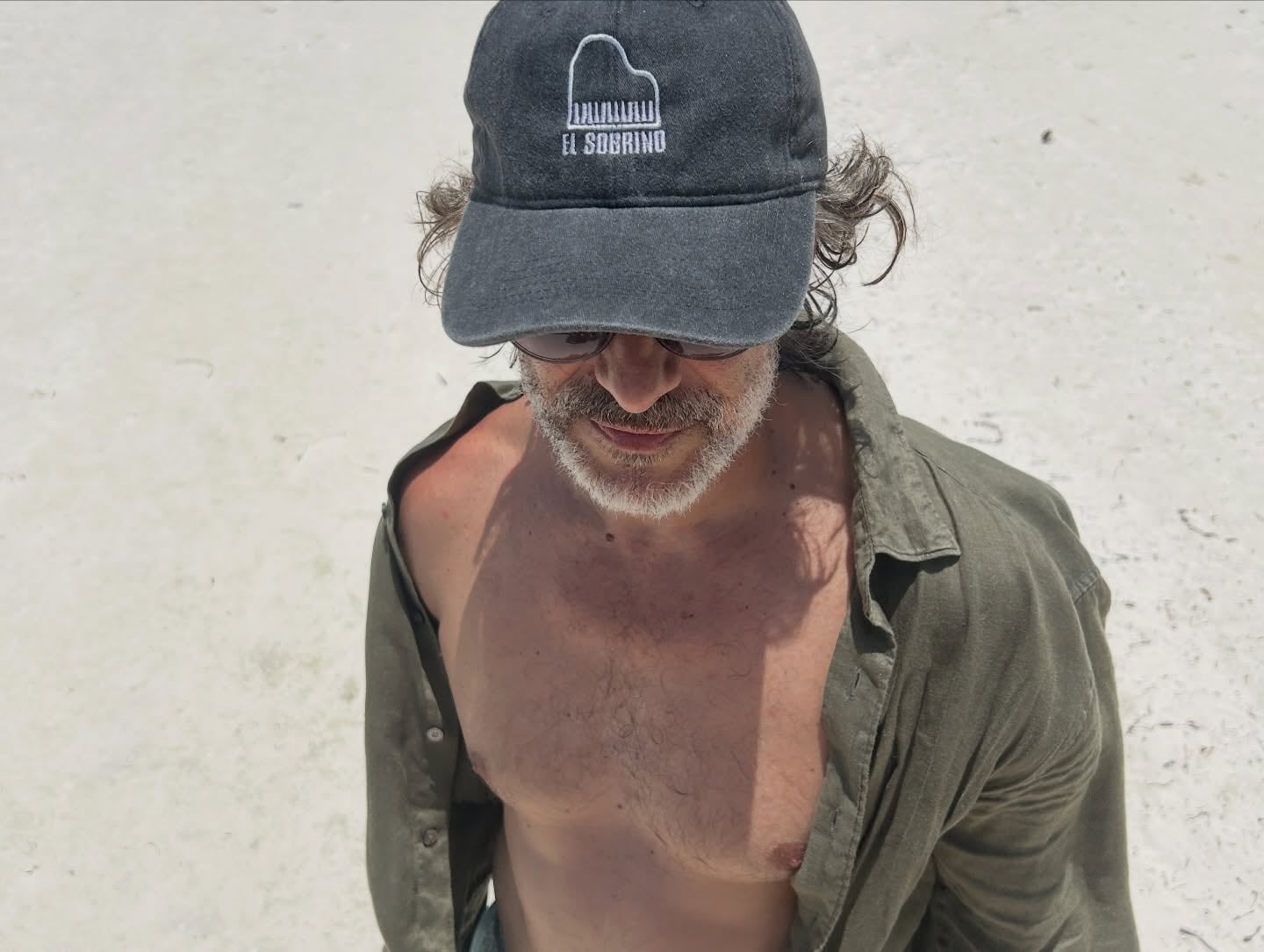 El actor, con gorra y camisa abierta, bajo el sol de la isla mexicana