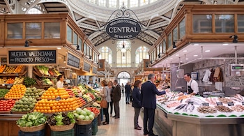 Puestos de verduras, frutas y pescado con vendedores y clientes en el interior del Mercado Central de Valencia.