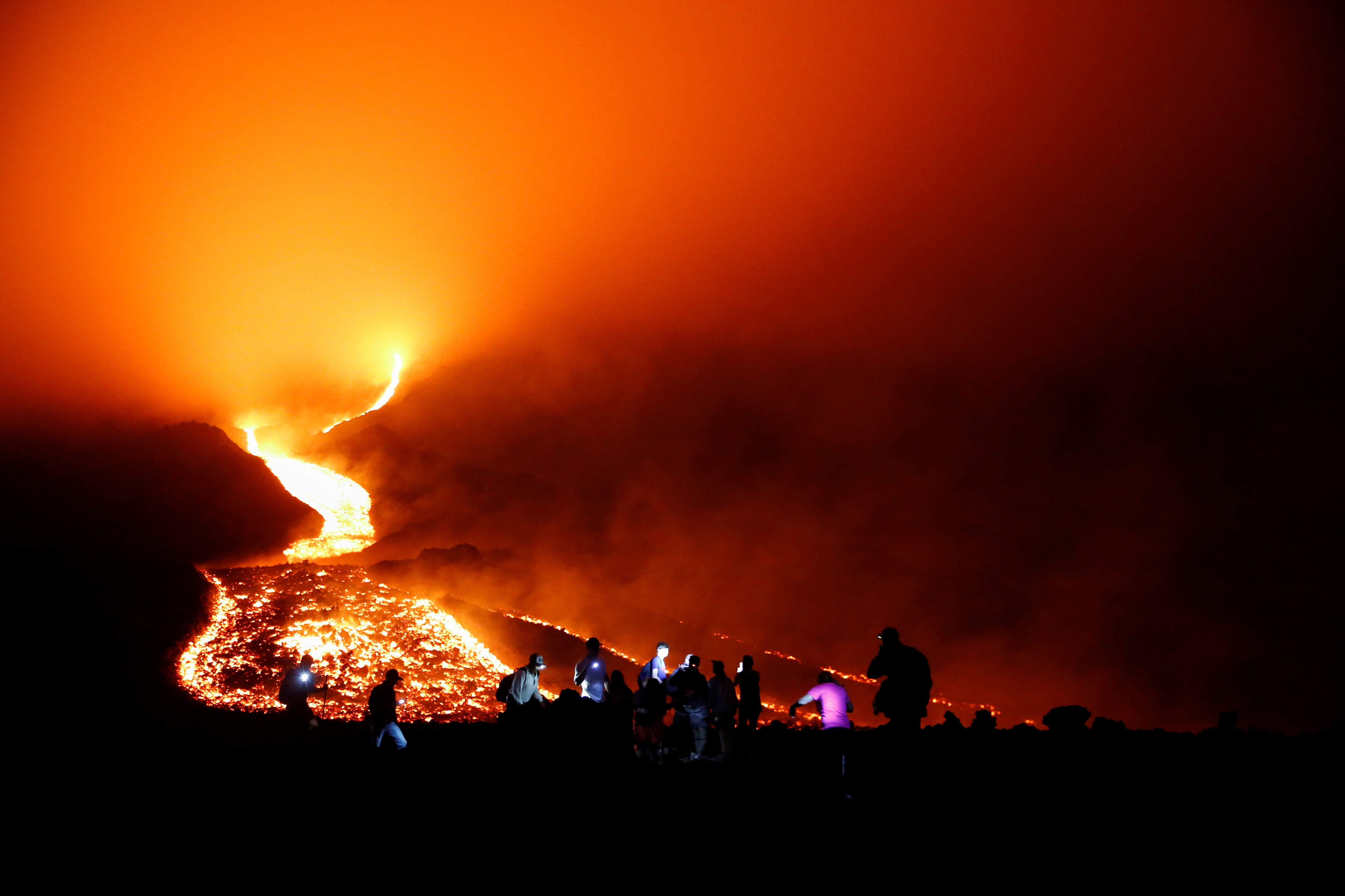 People watch as streams of red hot lava flow during an eruption of the Pacaya volcano at San Vicente de Sales municipality in the Escuintla region, Guatemala May 8, 2021. Picture taken May 8, 2021. REUTERS/Luis Echeverria