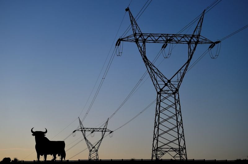 Líneas eléctricas que conectan torres de alta tensión y la figura de un toro del tamaño de una valla publicitaria. (REUTERS/Eloy Alonso/Imagen de archivo)