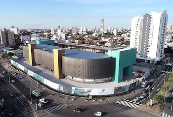 Vista aérea de un edificio moderno con fachada dorada y verde turquesa junto a una intersección vial con vehículos