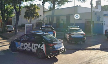Imagen de la Comisaría 15 en Rosario con su fachada blanca y azul, y dos vehículos policiales estacionados en la calle soleada