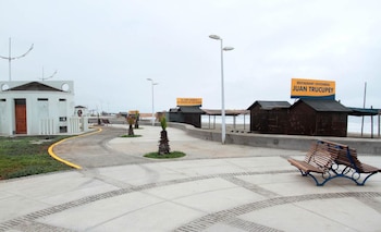 Un paseo peatonal junto al mar con ciclovía, bancas de madera, pequeñas palmeras, luminarias y casetas de madera con carteles