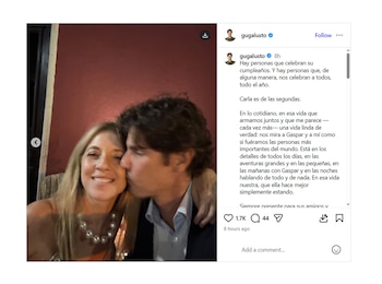 Martín Lousteau, un hombre de cabello oscuro, besa la mejilla de Carla Peterson, una mujer rubia con collar de perlas, quien sonríe a la cámara